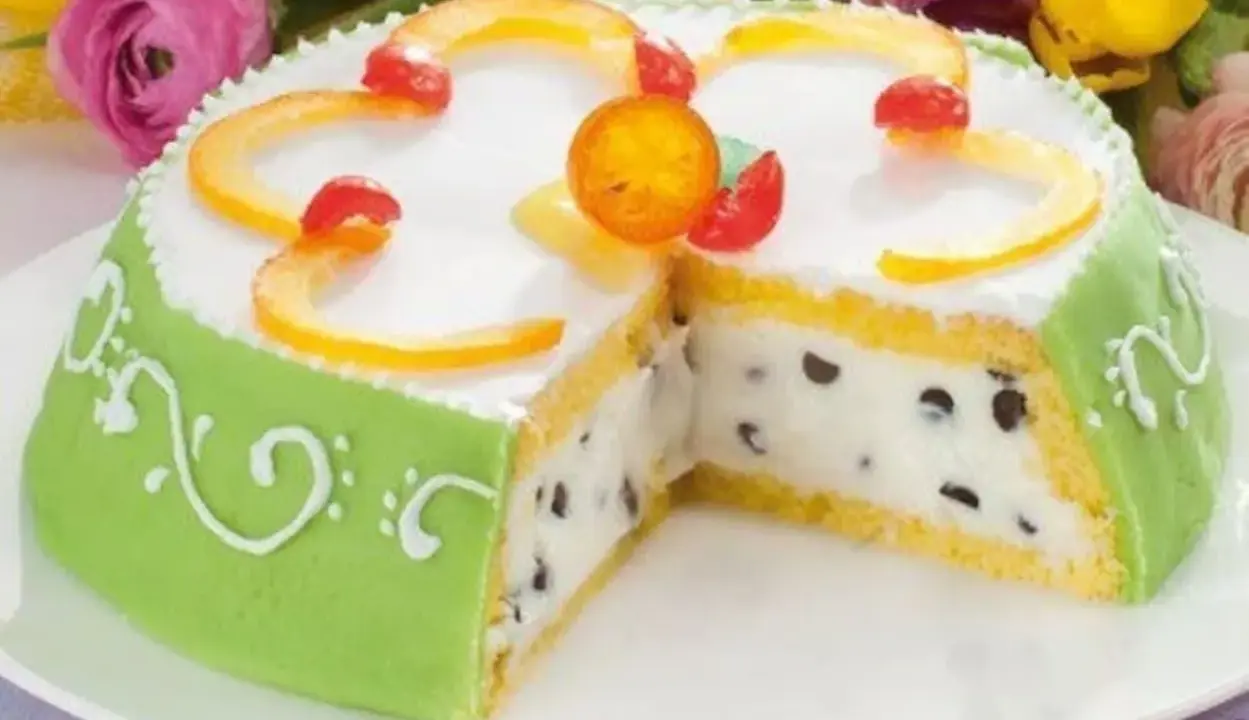 A slice of green marzipan-covered Cassata Siciliana cake with candied fruit and chocolate chips.