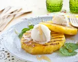 Grilled pineapple slices topped with scoops of vanilla ice cream and drizzled with honey.
