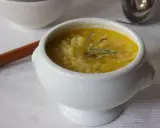 A white bowl of creamy potato soup with small pasta and a sprig of rosemary.