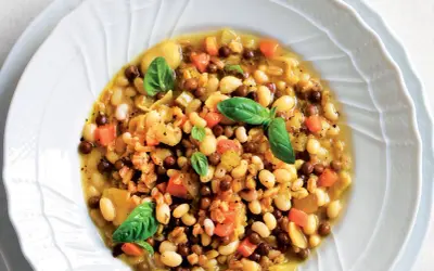 A hearty bowl of farro soup with white beans, lentils, carrots, and basil.