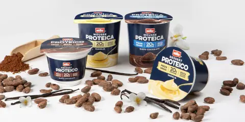 Müller protein desserts in chocolate and vanilla flavors, with cocoa beans, vanilla pods, and a scoop of cocoa powder.