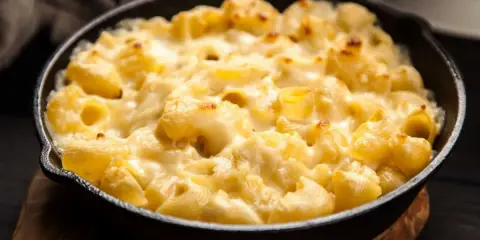 Baked pasta with creamy cheese sauce in a cast iron skillet.