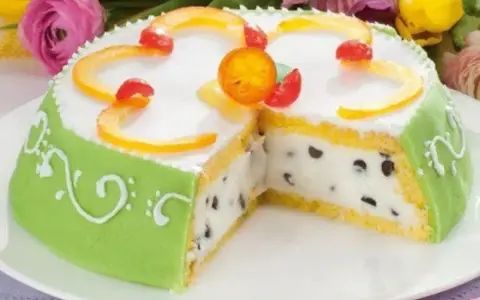 A slice of green marzipan-covered Cassata Siciliana cake with candied fruit and chocolate chips.