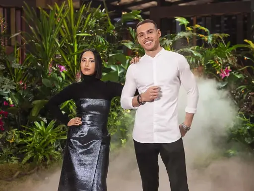 Two judges from MasterChef Dessert Masters Italia stand in front of a lush green backdrop with smoke effects.