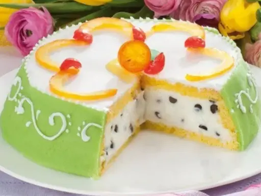A slice of green marzipan-covered Cassata Siciliana cake with candied fruit and chocolate chips.