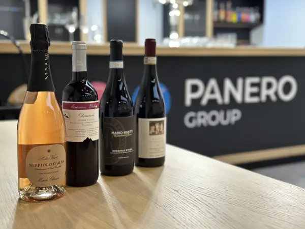 Four bottles of wine, including a rosé sparkling wine, on a wooden table with a blurred background.
