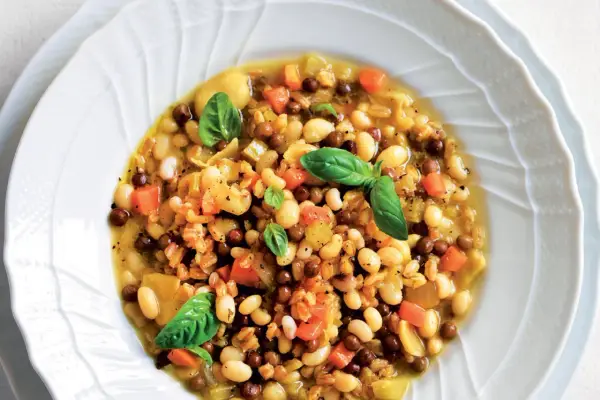A hearty bowl of farro soup with white beans, lentils, carrots, and basil.
